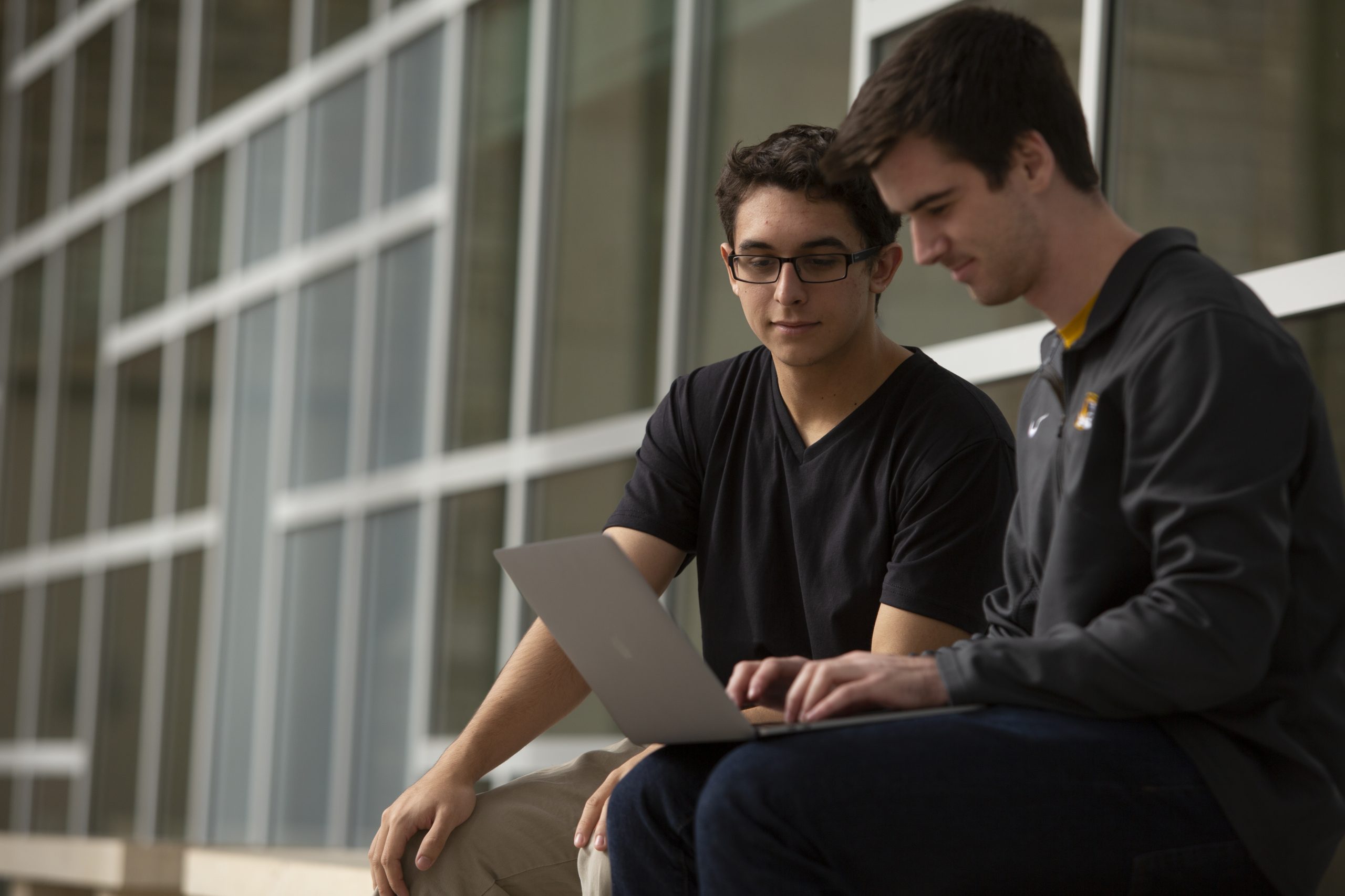 Two students look at a laptop outside the MU Student Center