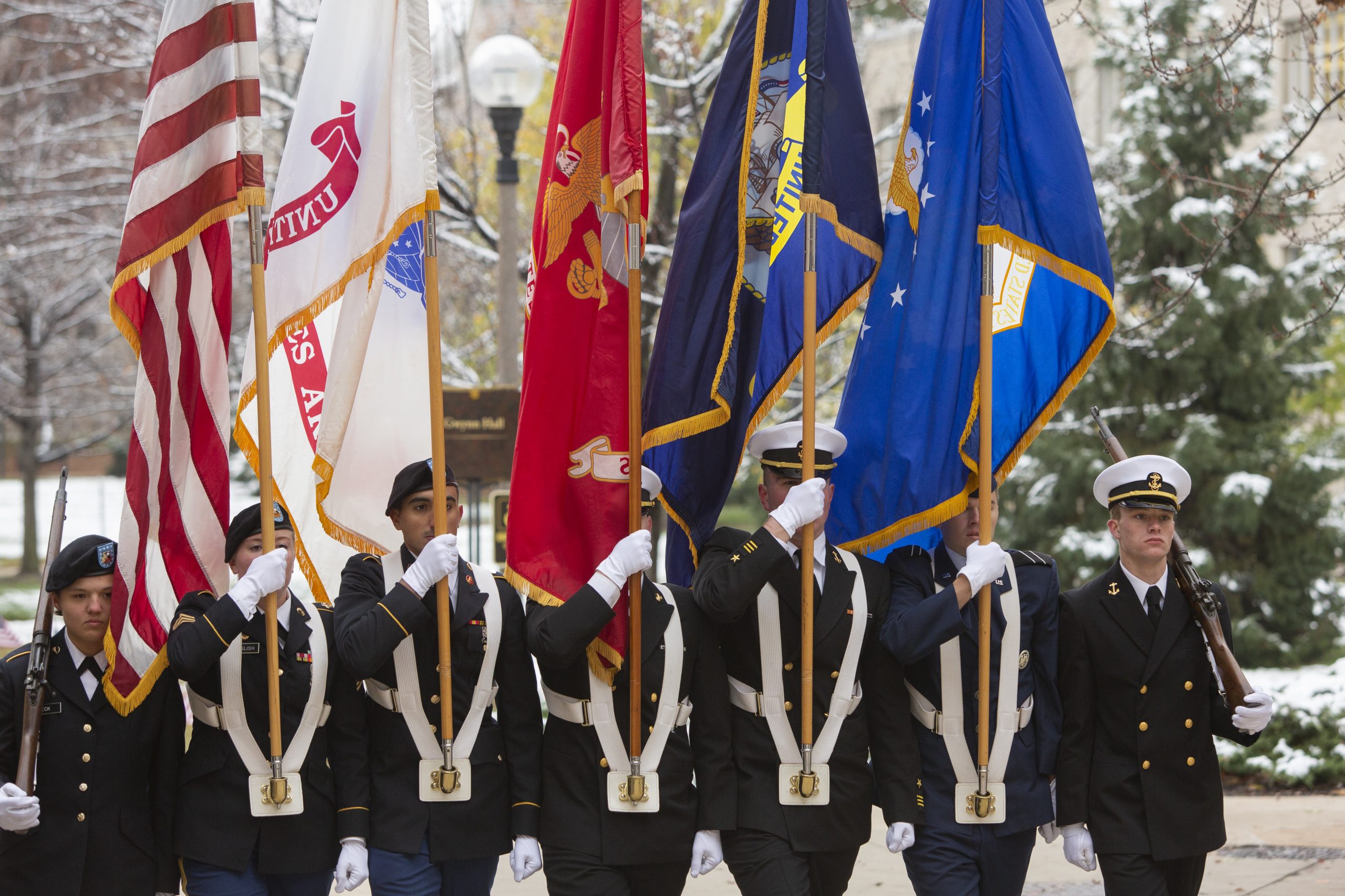 Students in military uniform hold flags