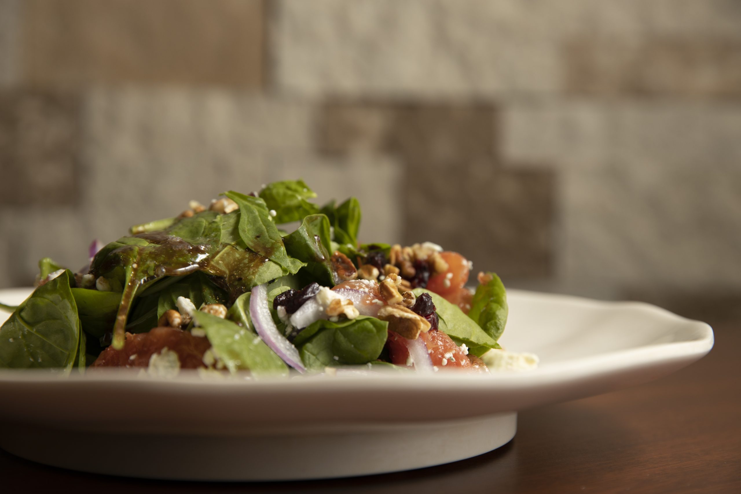 A spinach grapefruit salad on a white plate