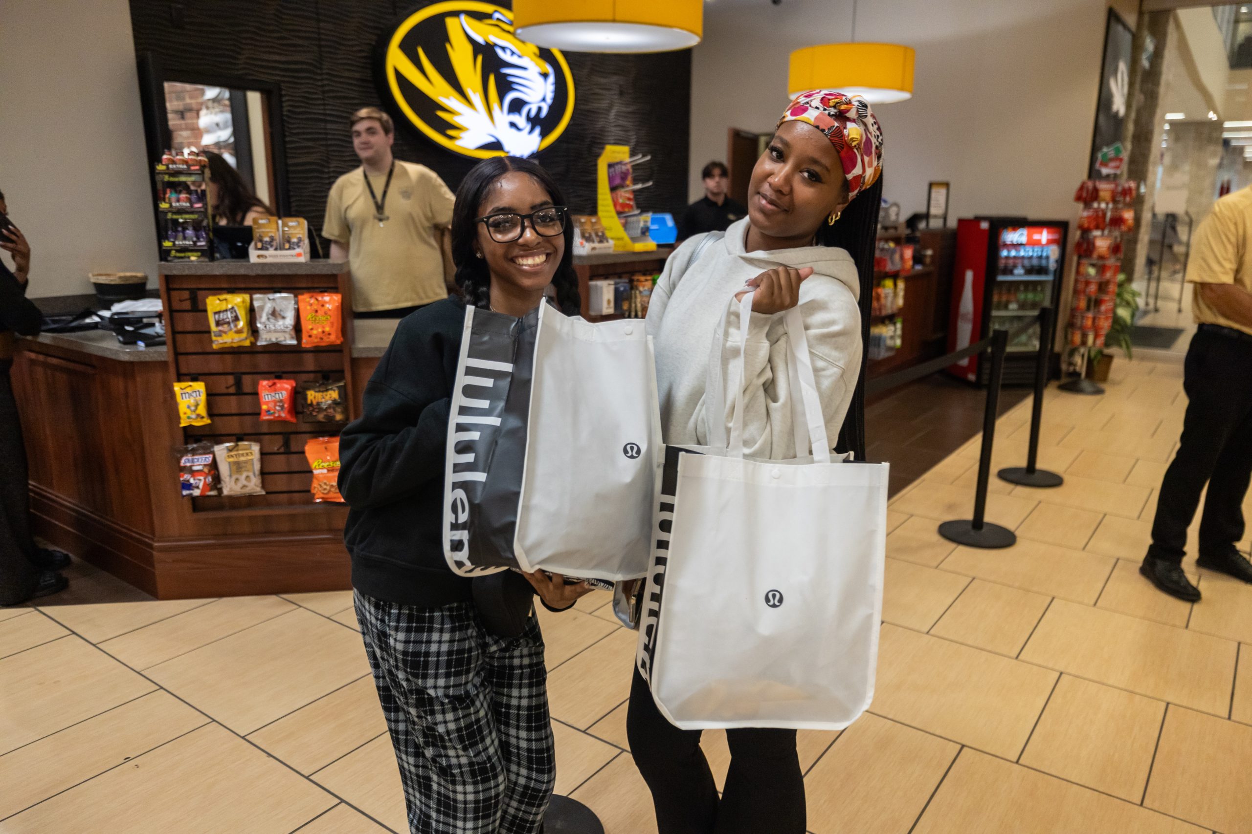 Two students hold shopping bags inside The Mizzou Store